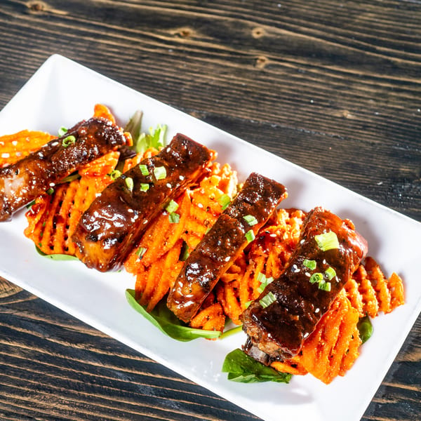 Glazed ribs with sesame seeds and green onions, served on waffle-cut sweet potatoes and spinach.